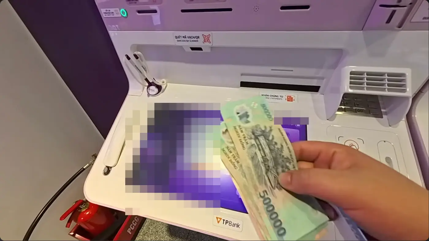 ATM 앞에서 베트남 50만 동 지폐를 든 손