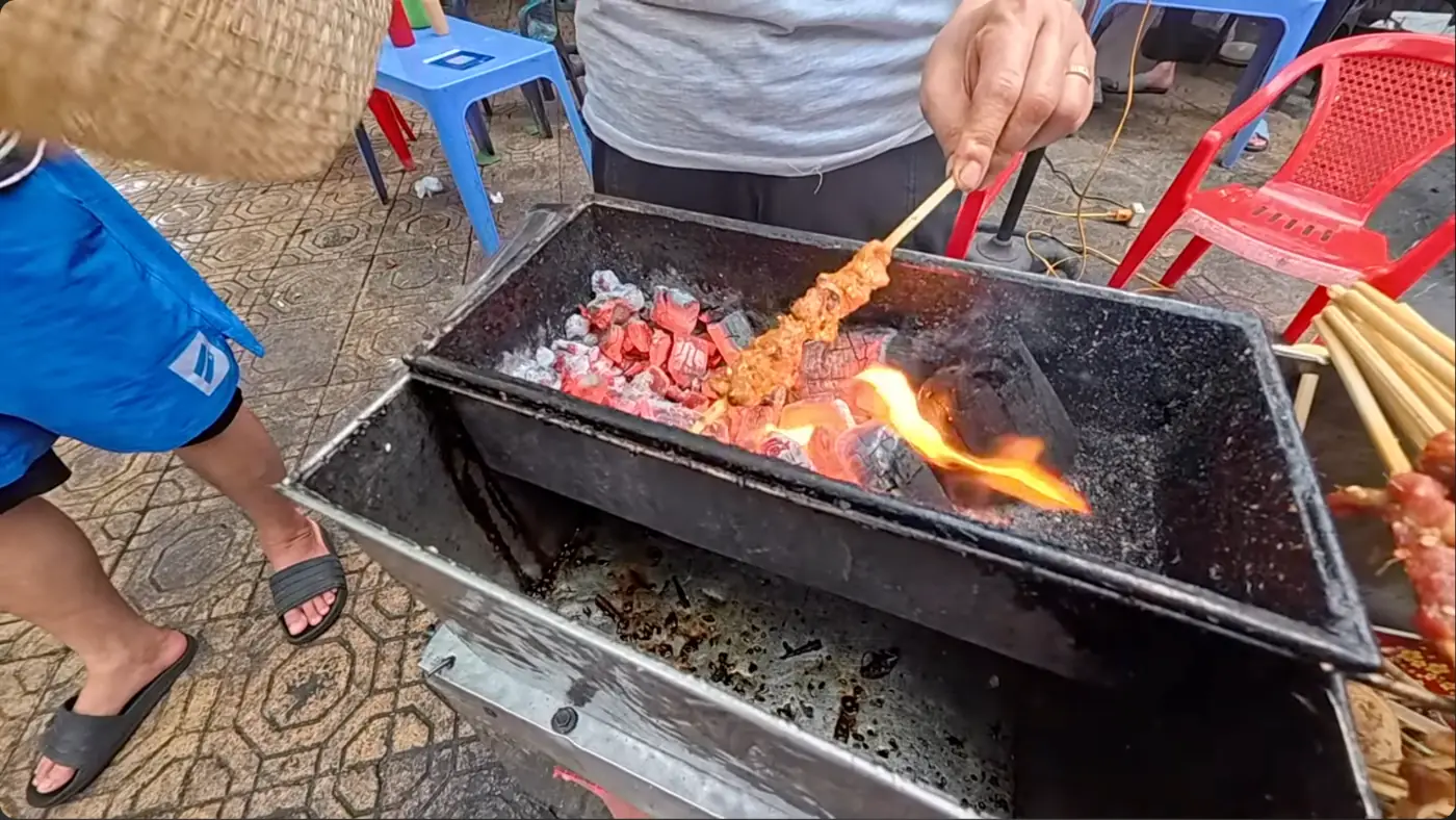숯불 위에서 칠리소스를 바른 돼지고기 꼬치를 굽는 모습
