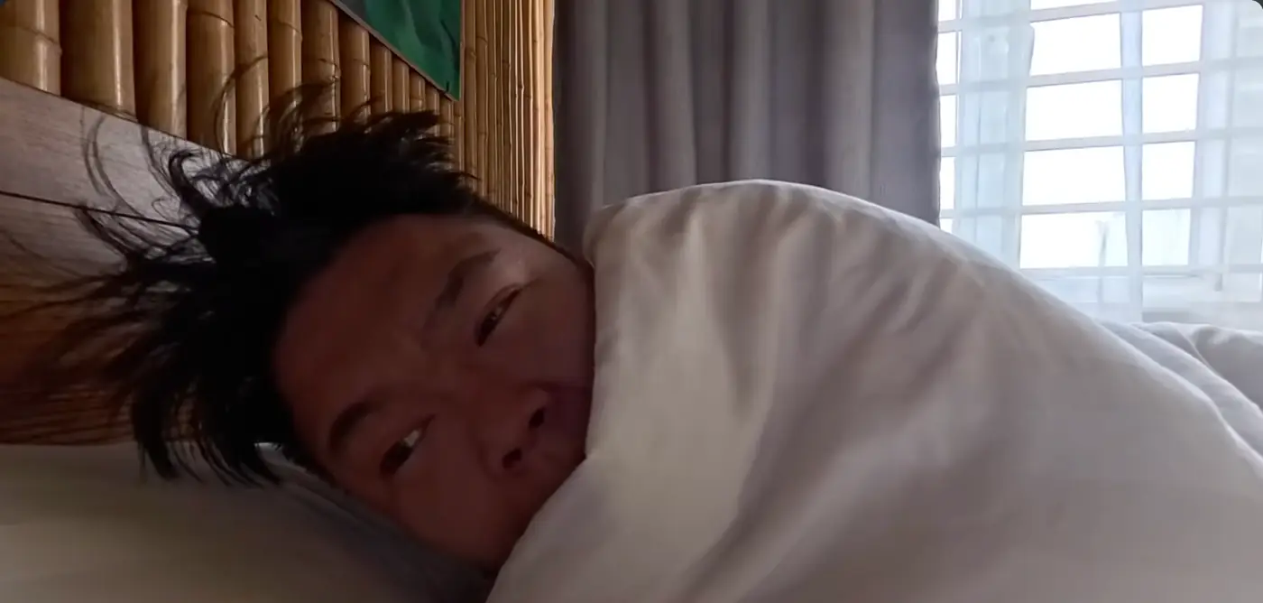 숙소 침대에 이불을 감고 누워 있는 모습