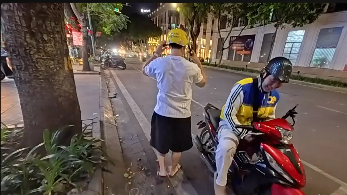 밤길에서 노란 헬멧을 쓰는 동행과 오토바이에 앉은 기사