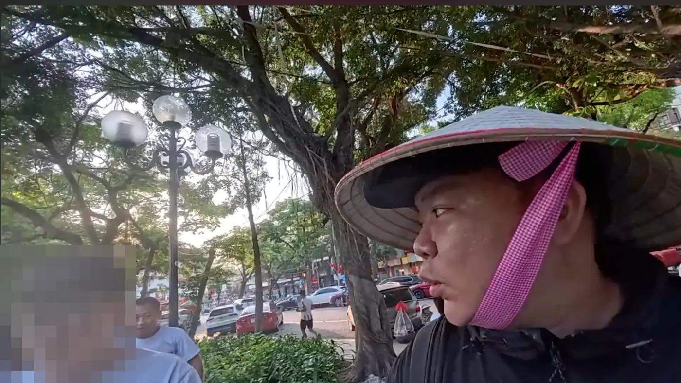 베트남 전통 모자 논라를 쓰고 호숫가 가로등 아래 선 모습