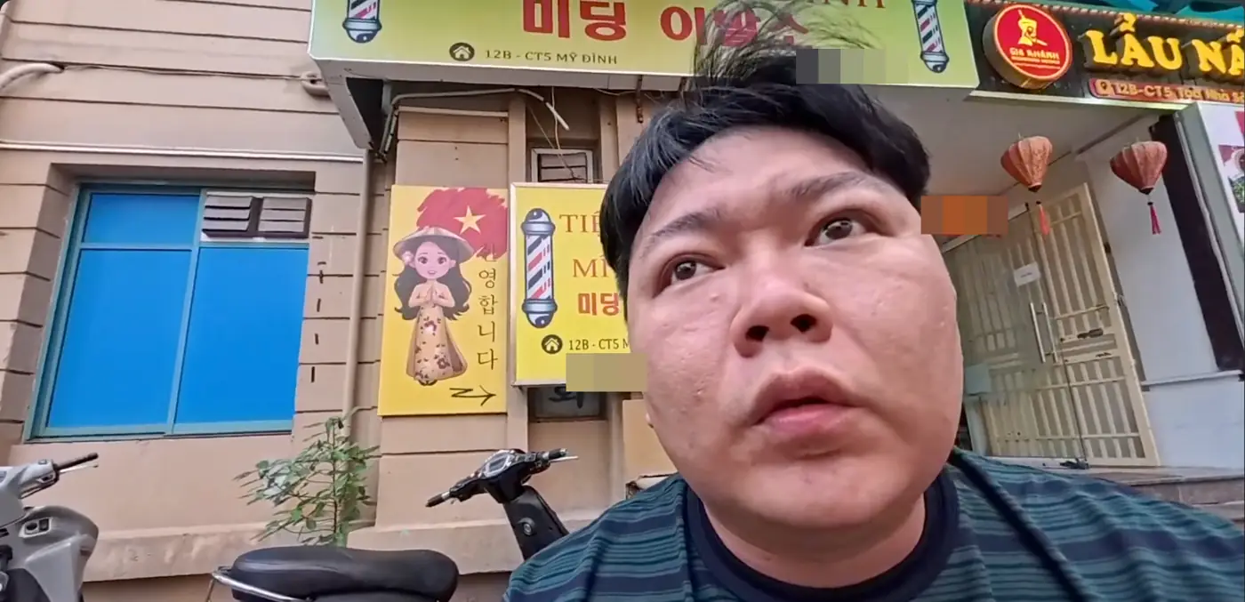한글로 미딩 이발소라고 적힌 노란 간판 앞에 선 모습