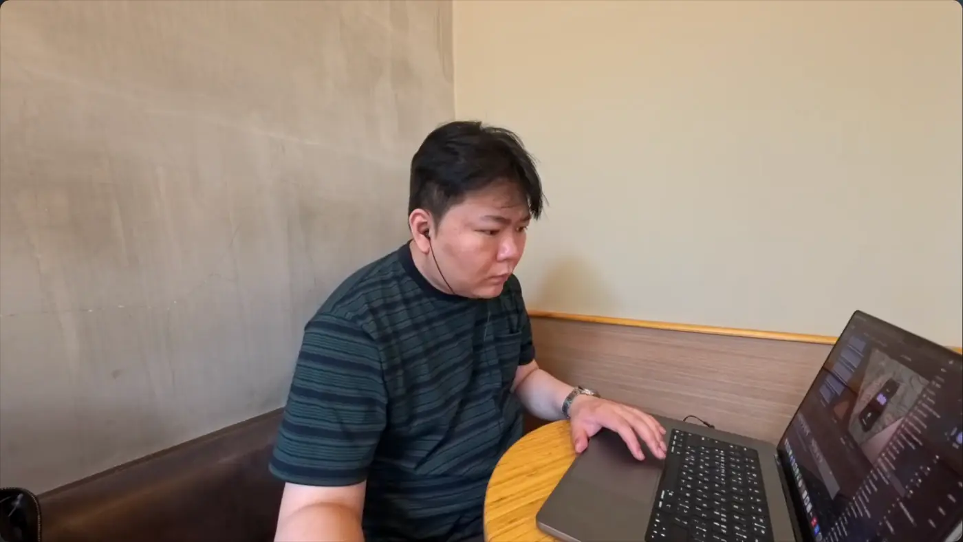 카페 구석 둥근 탁자에서 노트북으로 작업하는 모습