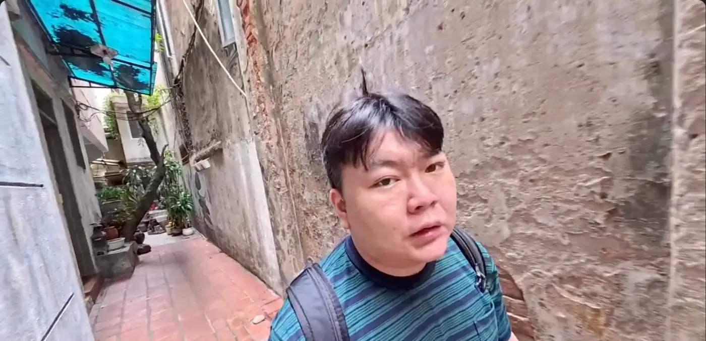 벽이 낡은 하노이 좁은 골목에 선 모습