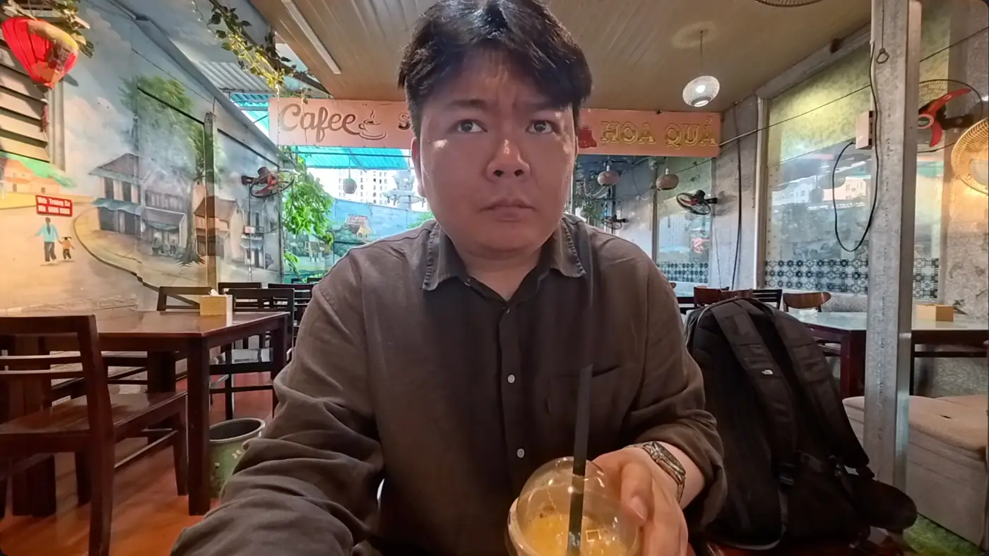 하노이 골목 벽화가 그려진 카페에서 망고 음료를 앞에 두고 앉은 모습
