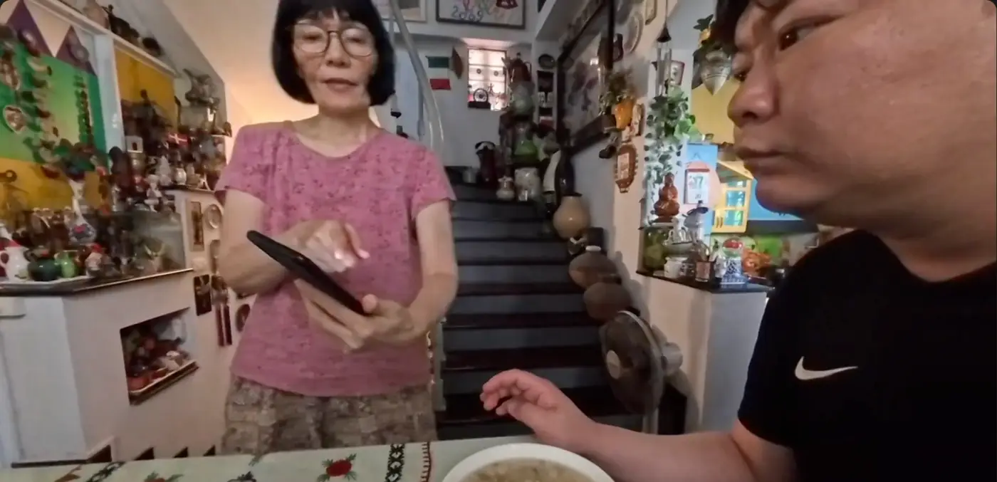 휴대폰을 들고 죽에 넣은 재료를 설명하는 숙소 주인 아주머니와 앞에 놓인 죽 그릇